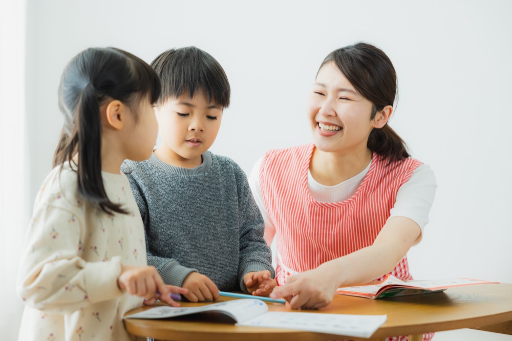 園で先生と一緒に机に向かう子どもたちの写真